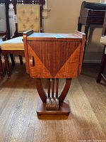 Front view of the wooden side table showing geometric inlay door design and curved pedestal base.