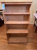 Front view of the solid wood blonde bookshelf showing four shelves and overall structure.