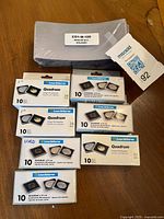 Photo of multiple coin collecting supplies including sealed and used Leuchtturm Quadrum coin holders in boxes and a plastic wrapped pack of medium bill holders.