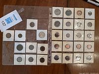 Two sheets displaying about 30 different collectible coins individually encased in cardboard holders with plastic windows, arranged in rows.