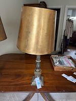 Photo of full lamp showing gold cylindrical lampshade and overall lamp structure on wooden table.