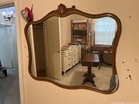 Full view of the large wall mirror mounted on hooks reflecting a room with furniture.