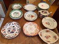 Full view of the lot including all plates, serving dish, teapot, and mini pitcher arranged on table.