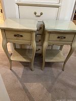 Front view of vintage pair of nightstands, one has a glass top, the other missing glass top.