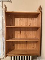 Front view of the solid wood bookshelf showing three shelves and vertical plank back panel.