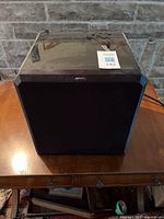 Front view of the Sunfire HRS-12 powered subwoofer showing black grille and glossy top surface with wear marks.