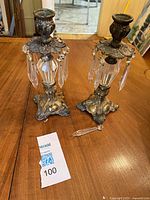 Pair of brass floral motif candlesticks with crystal pendants, cast ornate base, showing some tarnish and missing pendants.