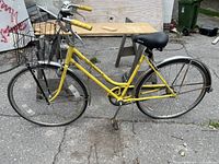 Full side view showing yellow frame, black saddle, and wire basket on front.