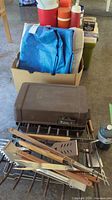 Coolers and tarps in box behind Coleman Turbo camp stove and BBQ accessories in front