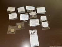Overview of multiple Canadian commemorative coins in plastic sleeves with handwritten labels describing each coin.