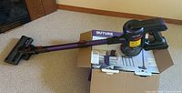 Full view of the Buture cordless stick vacuum cleaner assembled, showing the purple stick, black motor housing, and vacuum floor head.