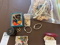 Overview image of diverse costume jewelry including cufflinks, pins, and a bag of beaded necklaces