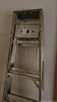 Side view of 6-ft aluminum ladder showing paint splatters and worn condition