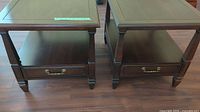 Pair of wooden side tables, showing front view with drawer and brass handles.