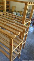 Photo showing two wooden slat shelving units stacked in garage, dusty with visible use marks