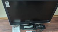 Sony Bravia 40-inch LCD TV with remote, power cord, and manual placed on hardwood floor.