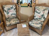 Front view of two wicker chairs with floral cushions and matching footstool