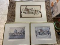 Three framed prints arranged on countertop showing the York Mills Hotel and two cityscapes by Inge Clausen.