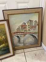 Framed print showing a building and a bridge with three arch openings, in beige and gold frame.