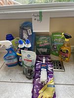 Various new cleaning supplies and pest control products arranged on a countertop in front of a window with a label 'Auction #47'.