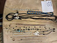 Top view of assorted vintage women's necklaces including bead strands, pendants laid flat on wooden surface.