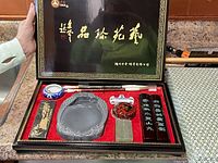 Chinese calligraphy set new in black glossy box with gold Chinese characters, red felt interior lining. Set includes ink stone, brush, brush rest, ink sticks, seal, and seal paste.