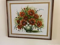 Framed floral print showing orange flowers, daisies, and blue blossoms in a green vase.