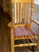 Photo of the wooden rocking chair showing front view with a cushion on the seat.