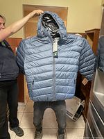 Front view of men's grey/blue Point Zero puffer jacket held up to show full garment with hood and zippered pockets.