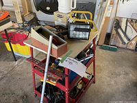 Wide view of red metal tool shelf loaded with various tools and accessories including a toolbox and work light