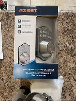 Photo of EZ Set electronic keypad deadbolt lock in original box on countertop.