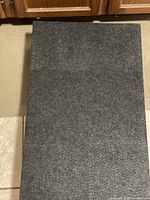 Top view of rectangular moving dolly showing gray carpeted surface.