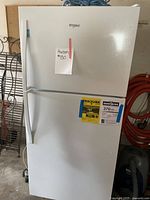 Front view of fridge showing upper freezer and lower refrigerator doors, Whirlpool logo and auction note