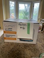 Box of Lumin CPAP UV Sanitizer with branding and auction label visible.