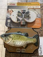 Photo of packaged Kidde LED Escape Light Smoke Alarm and Big Mouth Billy Bass wall hanging mounted on wood plaque.