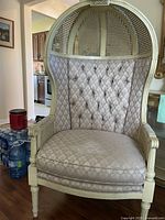 Front view of a hooded cane accent chair with tufted back and removable seat cushion