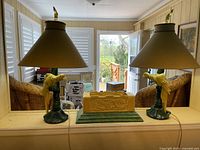 Overall view of two parrot lamps with shades and matching planter on green base