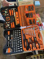 Opened black and orange tool case showing screwdrivers, pliers, clamps, wrenches and bits organized in slots