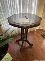 Full view of wooden table with glass top in front of a window