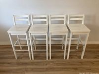 Four white gloss painted solid wood barstools front view