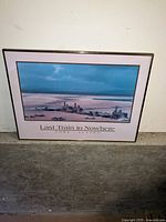 Framed color photographic print titled 'Last Train to Nowhere' depicting coastal buildings and docks in Nome, Alaska.