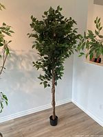 Photo of a single, tall artificial tree approximately 7.5 feet tall, set against a white wall on wooden flooring.