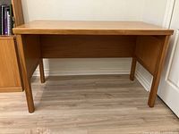 Front view showing entire wooden desk with kauri hardwood finish and four legs.