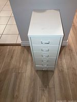 Small beige metal filing cabinet with six drawers, viewed from above, showing handles and top surface.