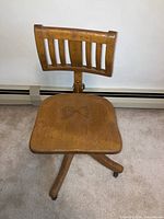 Front view of solid oak secretarial chair showing contoured seat, vertical slat backrest, and caster base