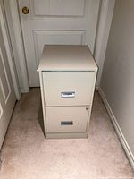 Front view of small beige Steel Works filing cabinet with two drawers and locking mechanism on bottom drawer.