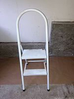 Front view of the white two-step folding stool showing two steps and curved handle.