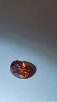 Close-up photo of a deep bright orange cushion cut spessartite garnet gemstone showing its facets and rich color.