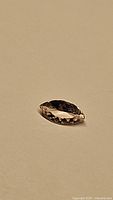 Photo of a loose marquis cut gemstone with champagne color, shown on a neutral background to highlight color and cut.