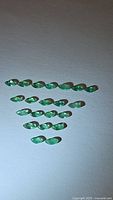 Top-down close-up of natural oval-shaped emeralds arranged in rows showing clarity and color